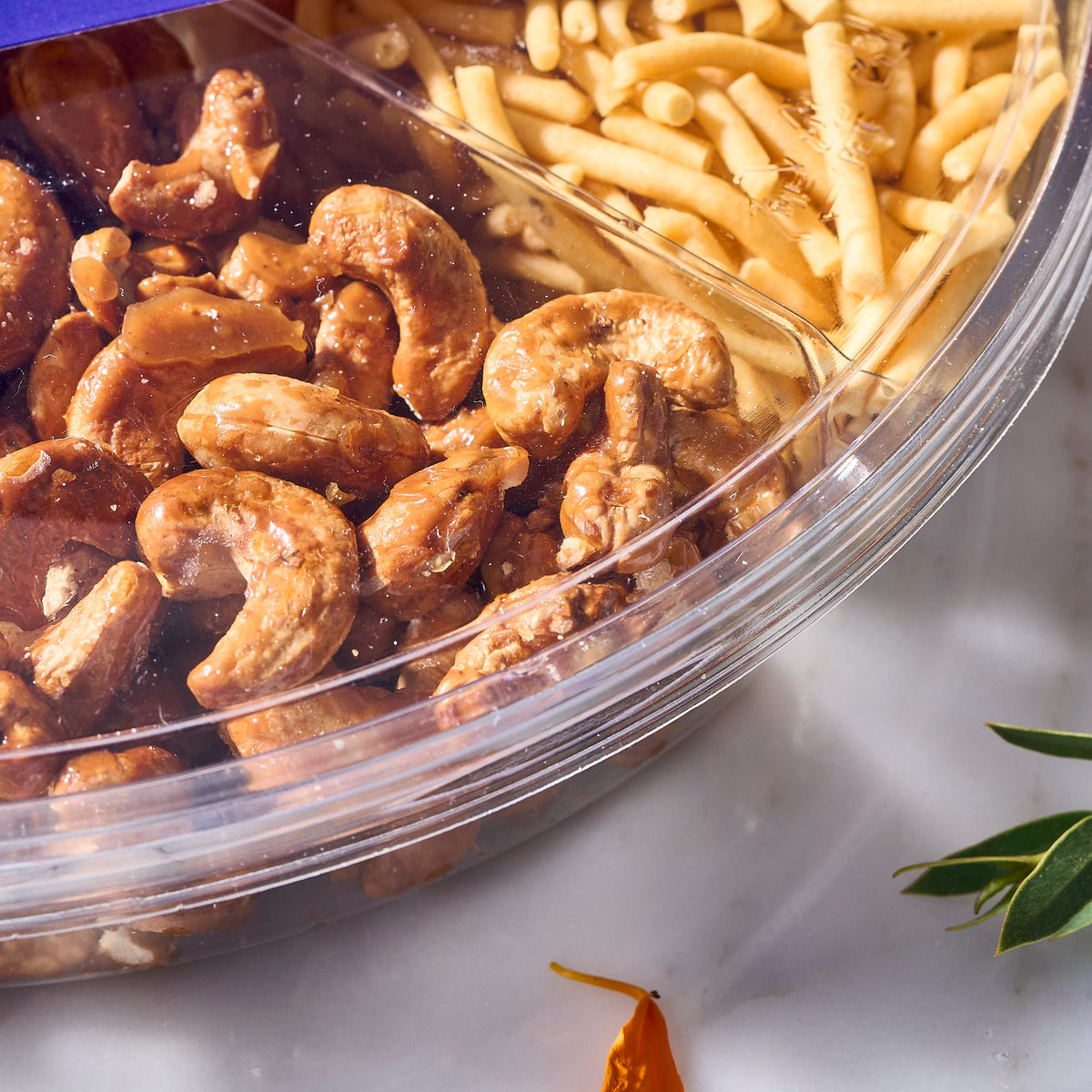 Close-up of glossy Honey Roasted Cashews beside murukku in the Deepavali Nuts & Snacks Tray