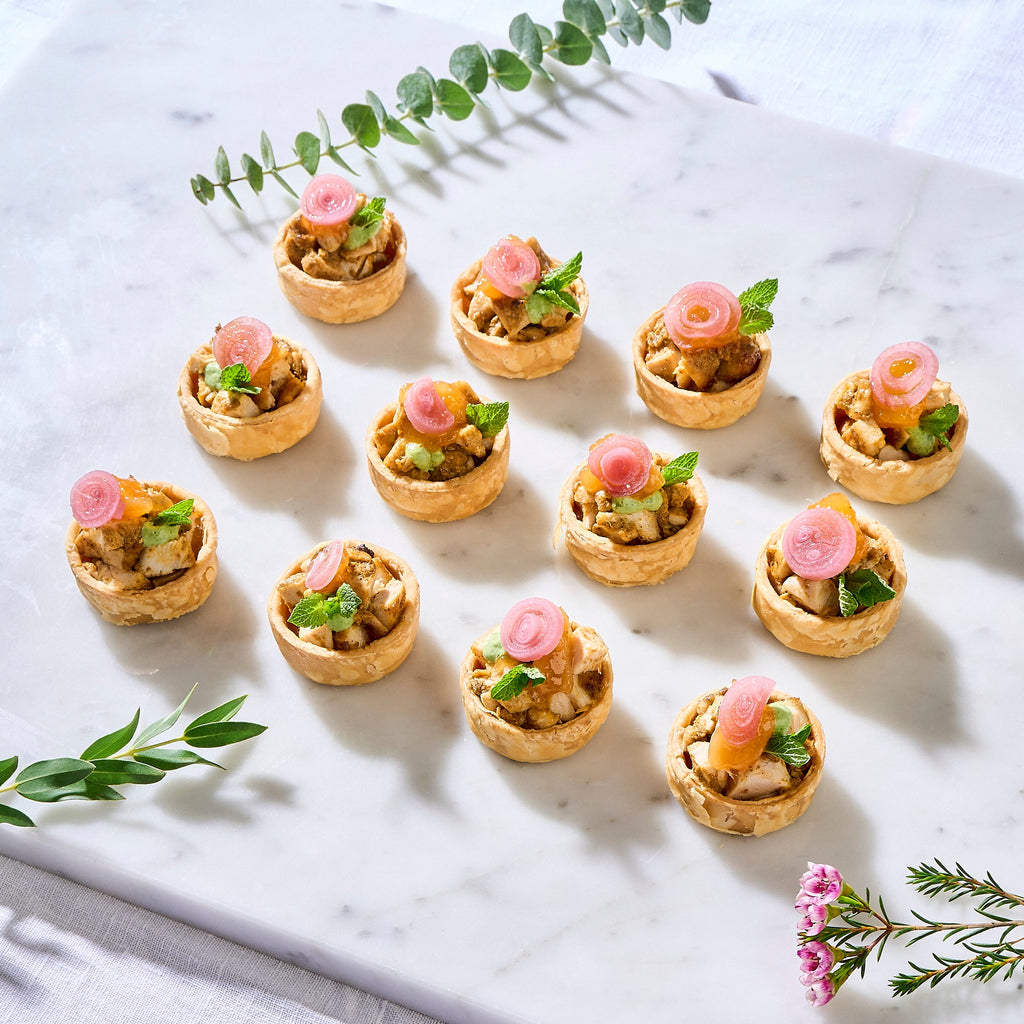 Twelve Chicken Tikka Tarts on a marble board, a halal Deepavali canapé with mint and pickled onion